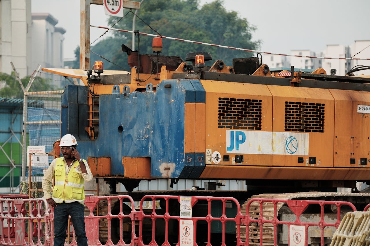 The Art of Drawing Readers In: Your attractive post title goes here Worker on phone at construction site with large machinery in urban setting.